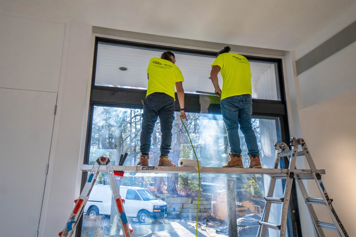Professional installers applying residential window film to large windows in a Highland Park home near Chicago.